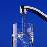 die Abbildung zeigt ein Glas, das mit Trinkwasser aus dem Wasserhahn gefüllt wird