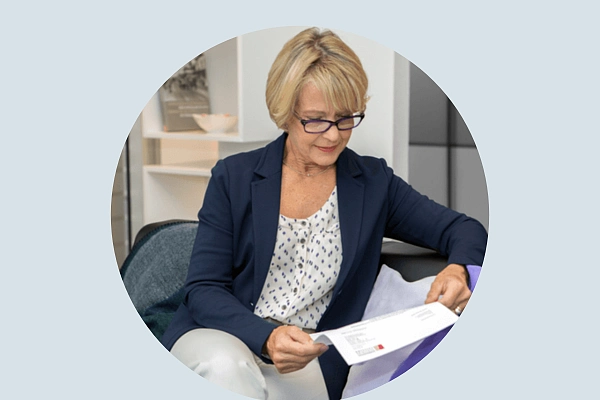 Ältere Frau mit Einladung zum Mammographie-Screening-Programm in der Hand schaut auf die Einladung